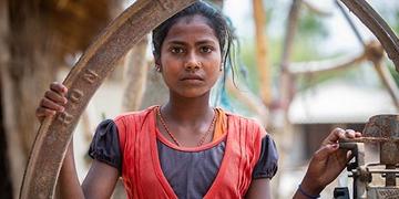 Nepal, a girl in orange stands outside of her family home Nepal, a girl in orange stands outside of her family home